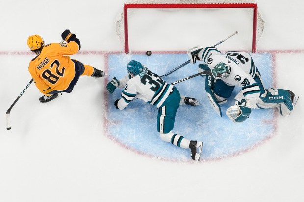 Nashville Predators center Tommy Novak (82) scores a goal past San Jose Sharks defenseman Calen Addison (33) and goaltender Magnus Chrona (30) during the third period of an NHL hockey game Tuesday, March 19, 2024, in Nashville, Tenn. The Predators won 8-2. (AP Photo/George Walker IV)