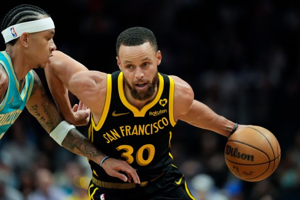 Golden State Warriors guard Stephen Curry drives to the basket past Charlotte Hornets guard Tre Mann during the first half of an NBA basketball game on Friday, March 29, 2024, in Charlotte, N.C. (AP Photo/Chris Carlson)