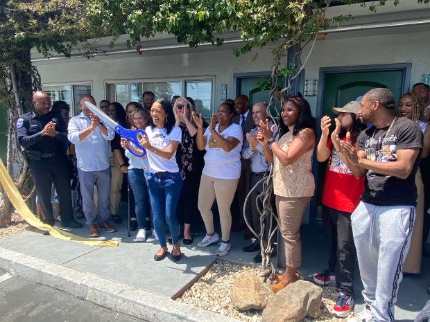 Homeless advocate Nichole Gardner holds a big scissor after helping cut the ribbon at the new Opportunity Village transitional housing center (formerly the Executive Inn) on 18th Street in Antioch on Thursday, April 26, 2023.