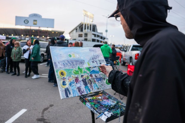 Artist Ryan Kelder paints live art depicting a Mexican band performing as Oakland Athletics fans dance during the boycott opening day block party in the parking lot during their MLB opening day game against the Cleveland Guardians at the Coliseum in Oakland, Calif., on Thursday, March 28, 2024. (Ray Chavez/Bay Area News Group)